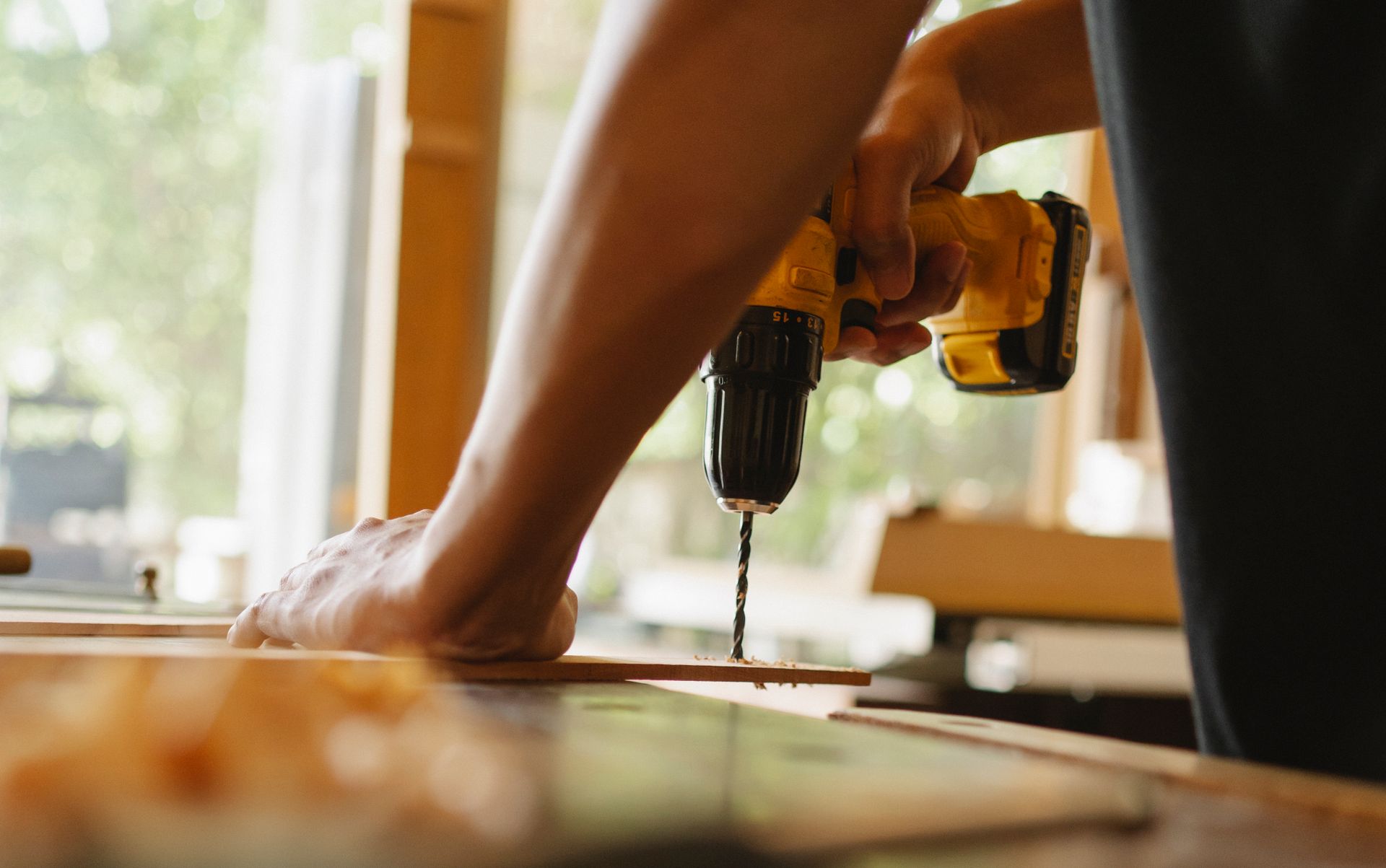 Contractor drilling into a wood plank on a workbench
